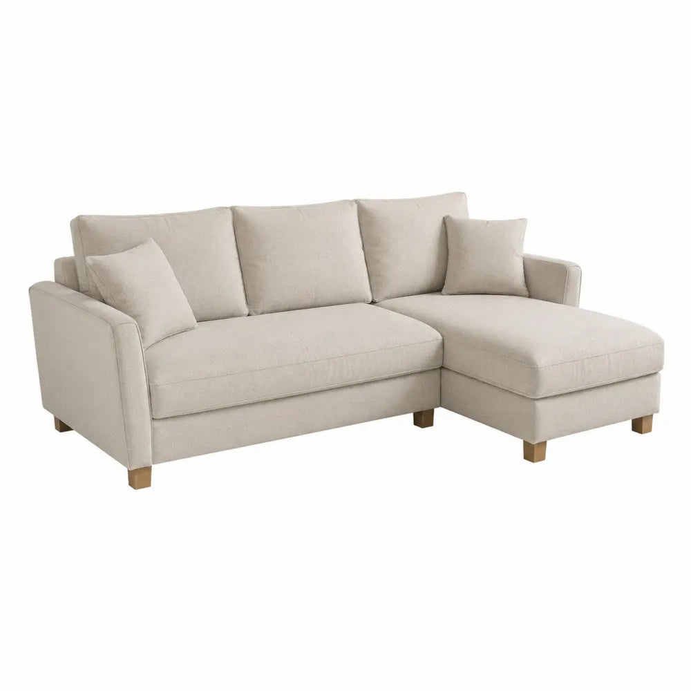 Kremowa sofa narożna z tkaniny z funkcją spania i drewnianymi nóżkami